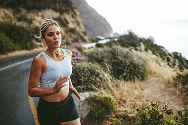 Determined female jogging along road in the rain.