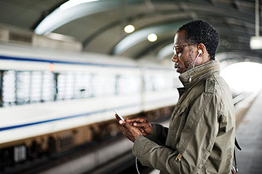 Make the most of your commute. Image of man on phone while waiting at the subway.