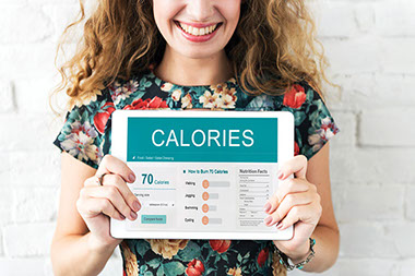 Image of women holding up tablet with calorie tracking.