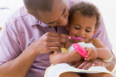 Image of father brushing toddler's teeth.