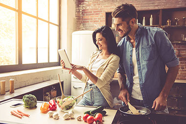 Couple in kitchen cooking together.