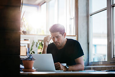 Image of man thinking about a problem at his computer.