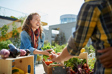 Woman tending stall at a farmers market and selling fresh vegetables. Woman tending stall at a farmers market and selling fresh vegetables.
