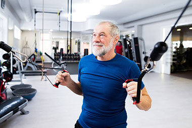 Fit senior man in gym working out with weights.