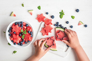 Kids hands cutting out star shaped watermelon. Kids hands cutting out star shaped watermelon.