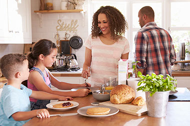 Family at home eating breakfast in the kitchen.