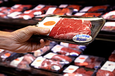Meat, poultry and fish. Image of a hand picking up a package of meat.