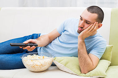 Man changing channels and feeling bored at home.