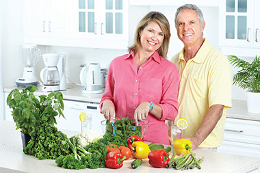 Image of middle-aged couple preparing food in their kitchen.
