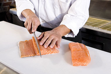 Image of a person cutting salmon.