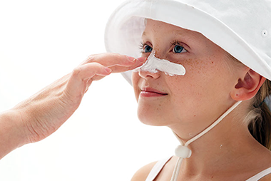Sun sense. Image of sunscreen being applied to a kid's face.