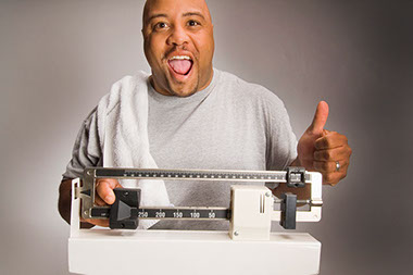Image of happy man with thumbs up as he weighs himself.