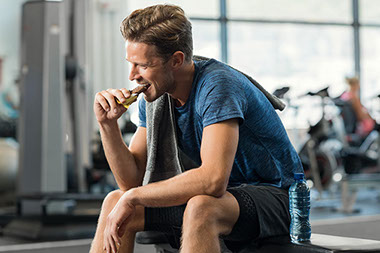 Man eating a power bar at the gym.