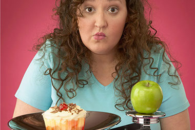 Image of women in front of a cupcake and apple on a scale.