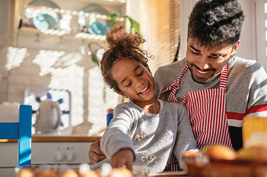 Father and young daughter cooking together.