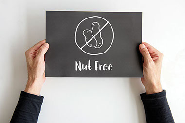 Image of hands holding sign that says "Nut Free".