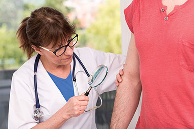 Image of doctor looking at patients rash on arm.