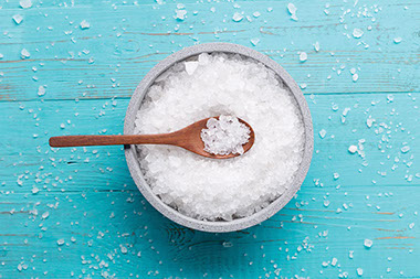 A bowl filled with salt and a wooden spoon.