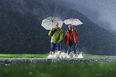 Unexpected ways to be happy (and healthy). Image of a couple jumping in a puddle while it's raining.