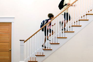 Home alone after school. Image of 2 school kids running up the stairs.