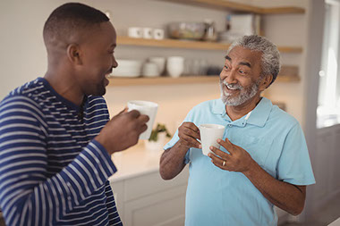 Father and adult son talking while drinking coffee.