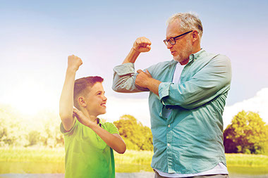 Grandfather and grandson flexing arms.