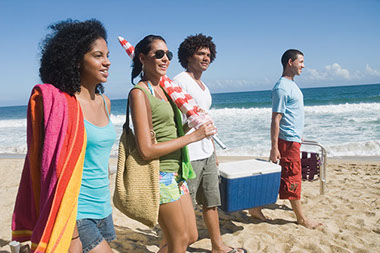 Image of teens at the beach with a cooler.
