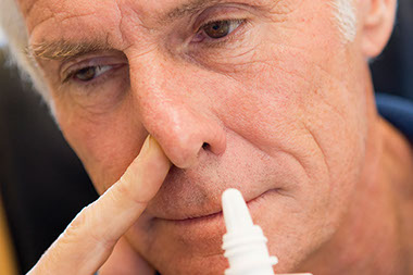 Image of man using a nasal spray.