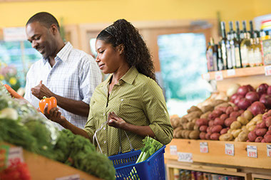 Organic? Comparing apples to apples. Image of couple at grocery store picking out peppers.