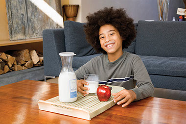 Five ways to fight childhood obesity. Image of boy with a glass of milk and an apple.