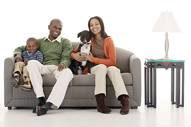 Image of family sitting on a couch with their pet dog.