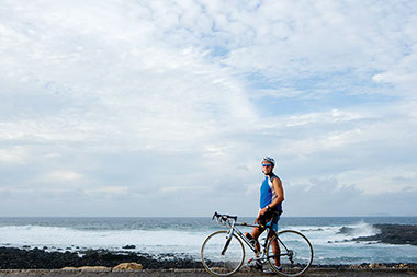 Image of man with bicycle along the beach.