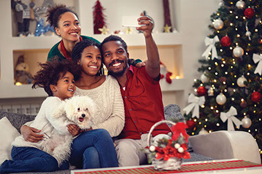 Family taking a selfie next to the Christmas tree.