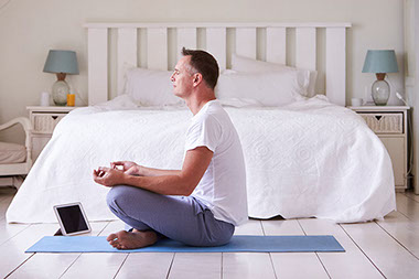 Man mediating on bedroom floor.