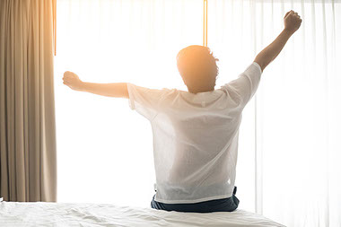 Image of man waking up and stretching in the morning.