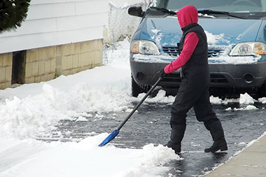 Image of person shoveling snow from the driveway.