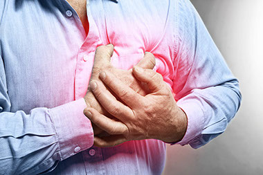 Close up image of man holding chest in pain.