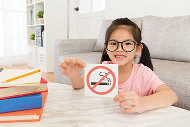 Child holding no smoking sign.
