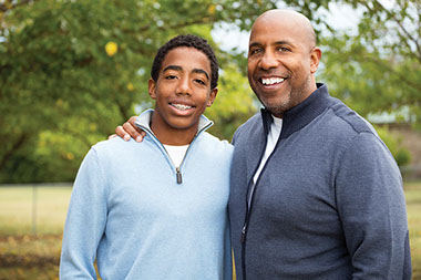 Father and teen son smiling.
