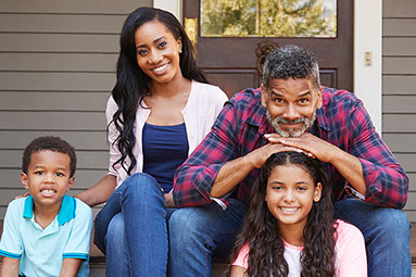 Family of 4 sitting outside their front door.