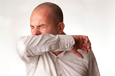 Image of man coughing into elbow.