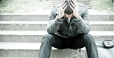 How to Spot a Possible Suicide. Image of man sitting on stairs with head down in his hands.