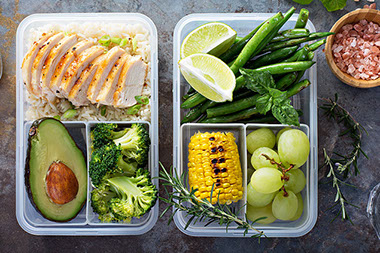 Healthy green meal prep containers with rice and vegetables.