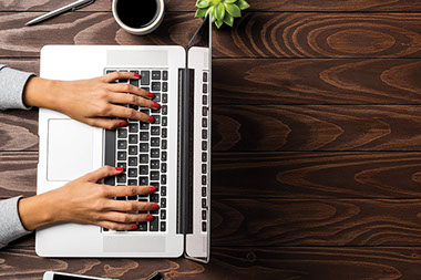 Close up of hands typing on laptop keyboard.