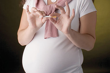Smoking and pregnancy. Image of pregnant women breaking a cigarette in half.