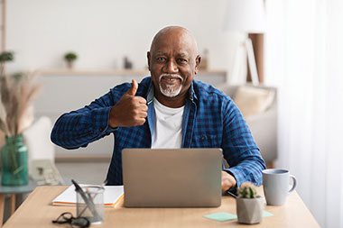Man on laptop with thumbs up.
