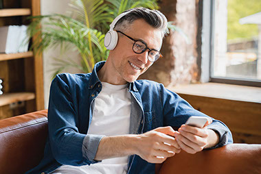 Man wearing headphones while using smartphone.