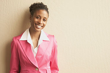 Image of middle-aged women smiling wearing a pink blazer.