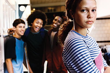 Image of kids laughing in the background at a young girl.
